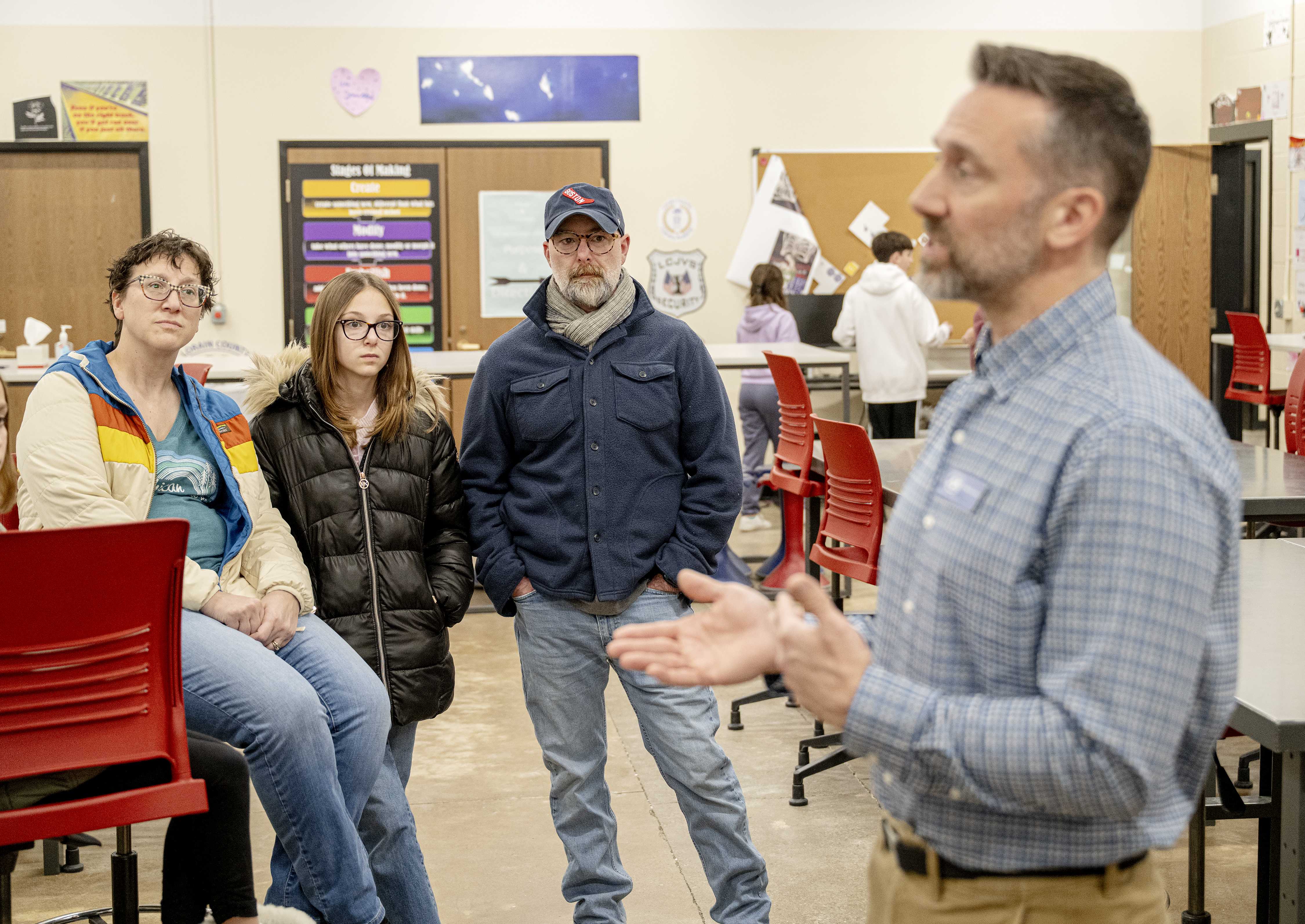 Male teacher speaks with potential family in classroom setting